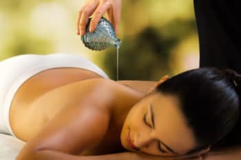 verser l’huile de massage ayurvedique sur le dos d'une femme