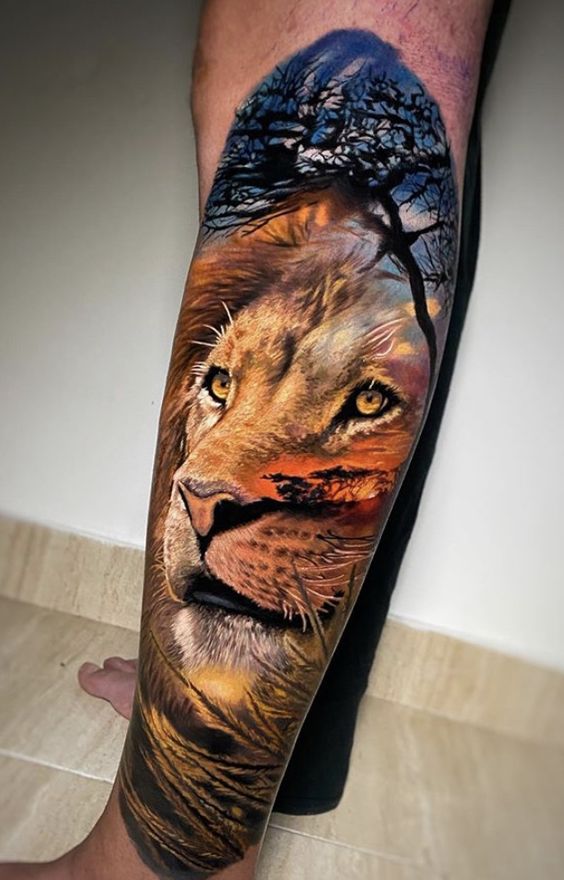 Tatouage Portrait D’un Lion Coloré & Savane Sur L’avant Bras Coloré