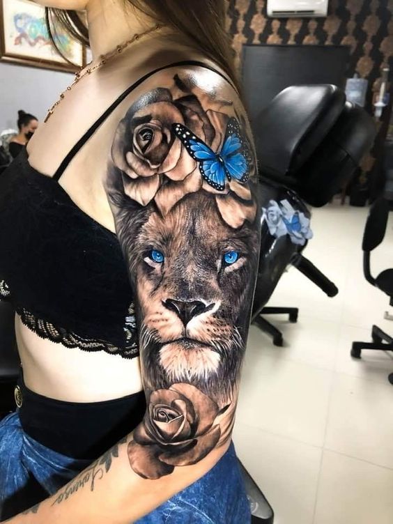 Tatouage Lion Avec Rose Noir Et Papillon Bleu Sur Le Bras 