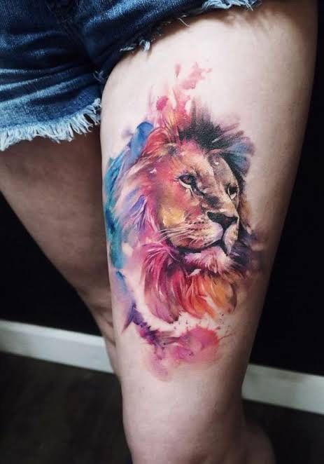 Tatouage Lion Aquarelle Avec Plumes Colorées Sur La Cuisse 