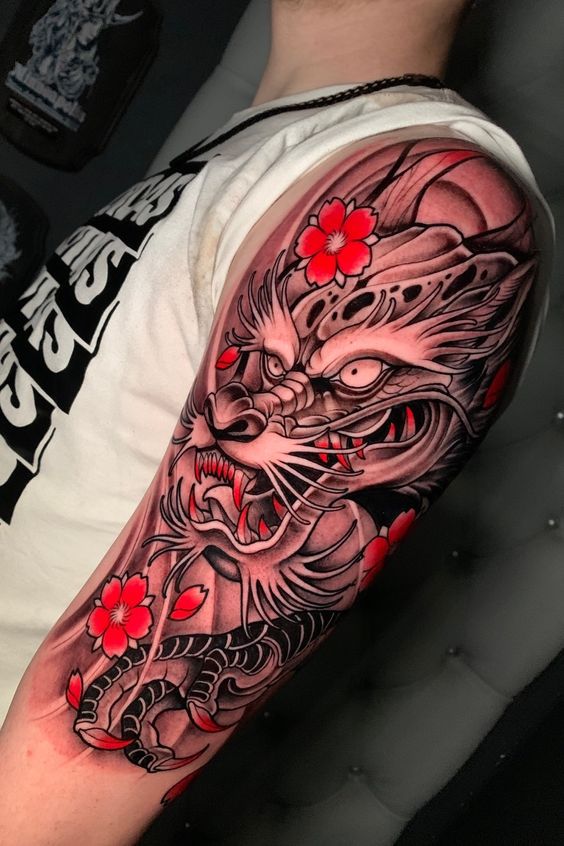 Tatouage Dragon En Noir Et Gris Et Fleurs Rouges Sur Le Bras 