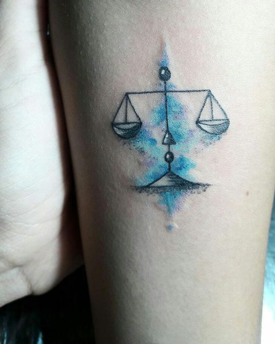 Tatouage Balance Et Aquarelle Bleue Sur Le Bras 