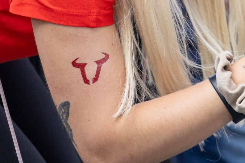 Tatouage Signe Taureau à L'encre Rouge Sur Le Bras 