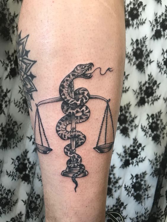 Tatouage Balance Et Serpent En Noir Et Gris Sur La Jambe 