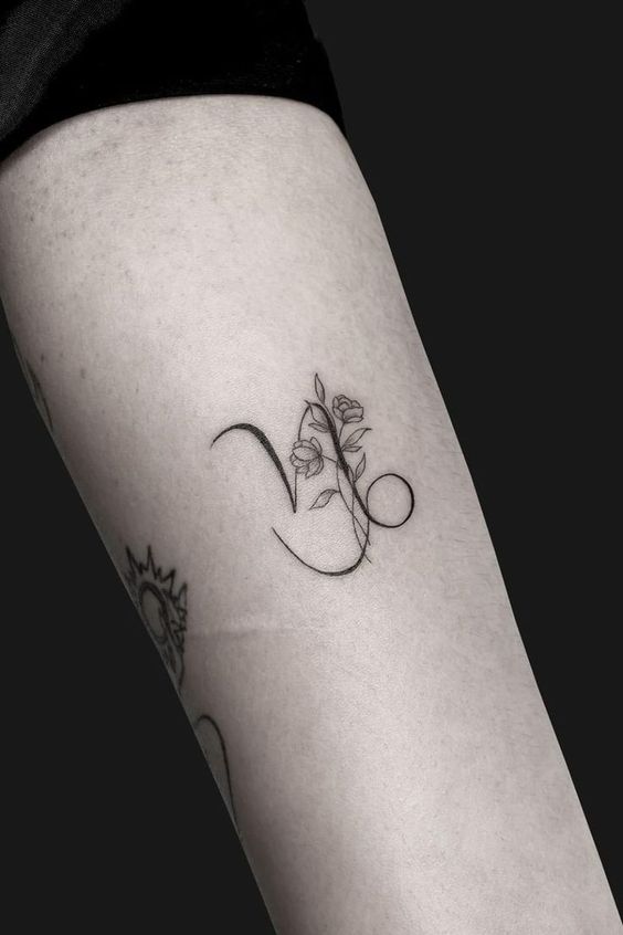 Tatouage Signe Capricorne Avec Fleurs Sur Le Bras 