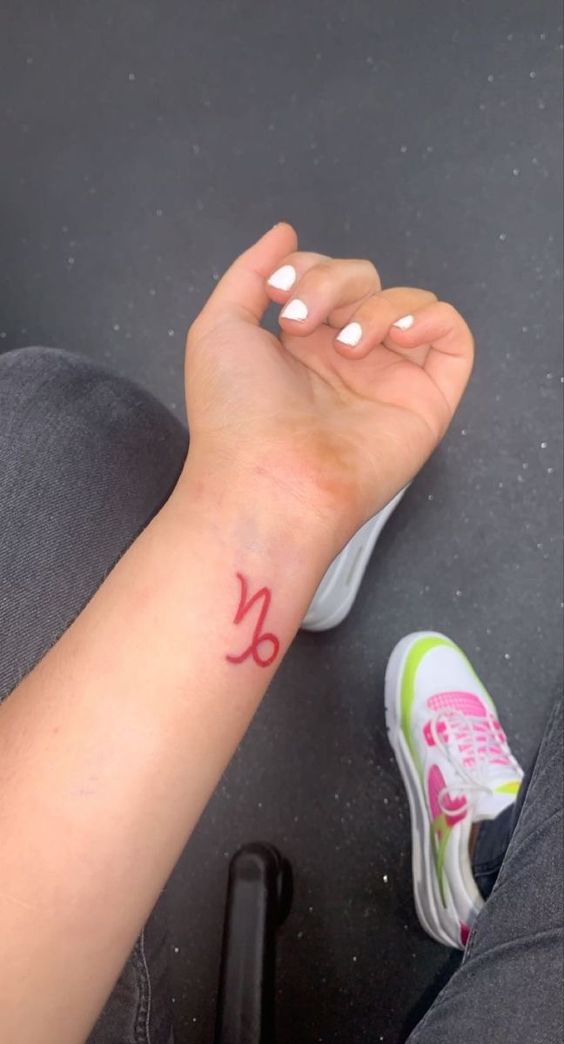 Tatouage Signe Capricorne à L'encre Rouge Sur Le Poignet 