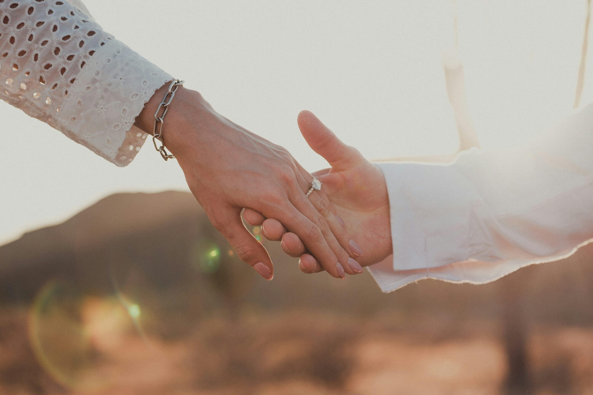 Couple Holding Hands With Engagement Rin